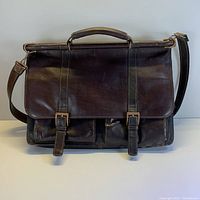Front view of Pelle Studio leather laptop bag briefcase with buckled flap and two small front pockets.