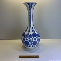 Front view of tall vintage blue and white vase with floral patterns, showing bulbous body and flared top.
