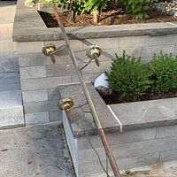 Full view of the metal and wood floor-to-ceiling lamp pole with three attached light fixtures.