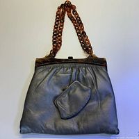 Front view of dark silver/pewter leather handbag with tortoise shell plastic chain strap with matching leather coin purse attached to front.