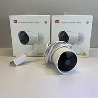 Two YI Outdoor Camera 1080p boxes with one camera and power cable displayed in front.