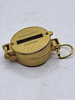 Closed view showing top lid with I H H Engineer's Compass 1960 engraving, gold-tone metal body, and keyring attachment