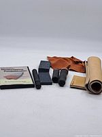 Photo showing the full set of the instructional DVD, leather glove, sharpening stones, leather roll pouch, small leather pouch, and black hand tools.