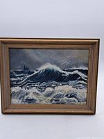 Full view of the framed painting depicting ocean waves with a sailboat under stormy skies.