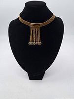 Front view of the gold tone mesh choker necklace displayed on a black bust stand.