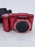 Front angle view of red Olympus SZ-14 digital camera showing lens and brand.