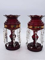 Front view of one red glass candle holder showing scalloped top, gold detailing, and hanging icicle prisms.