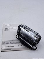 Sony digital video camcorder alongside original operating manual on clean white surface