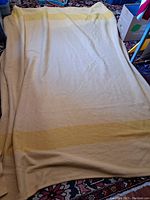 Full view of "Trapper Point" wool blanket laid out flat showing cream color with mustard stripes.