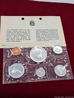 Photo showing the sealed original plastic package containing six uncirculated 1967 Canadian coins including silver dollar with flying goose design and an informational card behind