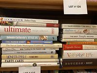 Stack of 23 cookbooks showing spines with titles related to pasta, baking, vegetarian, and seasonal cooking.