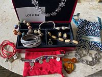 Full view of assorted costume jewelry including bracelets, rings, earrings, necklace, and jewelry box.