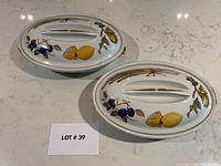 Pair of oval covered casseroles in Evesham pattern displayed on countertop with lot number card visible.