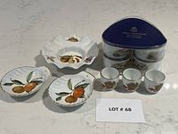 Top view of three Royal Worcester Evesham porcelain plates with botanical orange fruit design, four egg cups with bird design, and boxed set of six ramekins