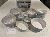 Whole lot with covered casseroles, ramekins, oval and round bakeware, and original packaging box on countertop.