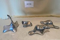 Photo of all four sculptures arranged on marble surface showing three abstract animals and one fox sculpture with wear.