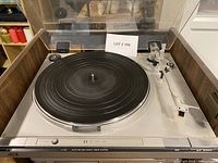 Front and top view of JVC L-A31 turntable with tonearm, platter, and control buttons visible under a clear dust cover.