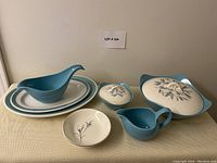 Full set of 8 ceramic serving pieces shown including tureen, gravy server, covered sugar, creamer, two oval plates, two small dishes.