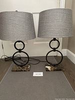 Pair of contemporary table lamps with gray fabric drum lampshades on floor with white door background