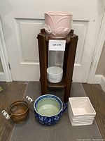 Wood plant stand holding various planters on and around it.