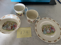 Set of 4 Royal Doulton Bunnykins items: two mugs, one bowl, one plate showing classic Bunnykins illustrations and patterns.