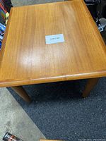 Top-down view showing the square surface of the teak table with visible grain and some light surface wear.
