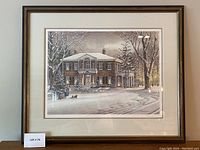Framed print of a large brick house in winter snow, with two mats and wooden brown frame, showing the full art and frame.