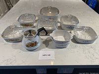 Full set of Corningware casseroles and tea pot arranged on countertop, showing various patterns including Cornflower Blue, Wildflower, and Spice of Life.