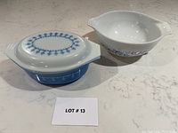 Two vintage PYREX casseroles shown side by side on countertop with lot number card.