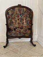 Front view of fireplace screen showing carved wood frame and tapestry panel