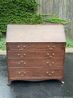 Front view of the Georgian mahogany secretaire desk showing the sloped front closed and four graduated drawers with brass handles and keyholes.