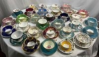 Wide overview of all 31 tea cup and saucer sets arranged on a table