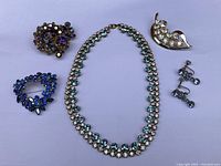 All items laid out: three brooches, necklace, pair of screwback earrings