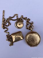 All items laid out: pocket watch, chain fob, two lockets