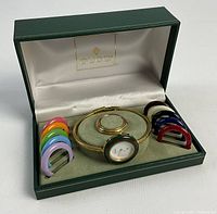 Open Gucci box showing bangle watch on display cushion surrounded by twelve colored bezel rings