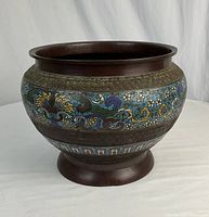 Front angled view of the large bronzed jardiniere, showing floral cloisonne details and round shape.