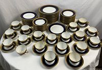 Full overview of cobalt blue and gold trimmed china set including plates, cups, and saucers