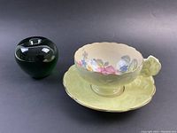 Tea cup and saucer set displayed together with unrelated green vase