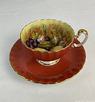 Front three-quarter view of teacup and saucer showing exterior color, interior design, and gold trim