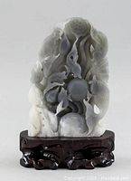 Front view showing detailed jade carving of fish and lotus with openwork holes on wooden stand.