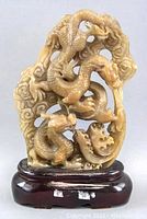 Front view of the carved yellow jade double dragons statue on a wooden base.