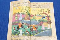 Hand painted illustration inside the book showing a detailed scene with horses, people, trees, water, and animals.
