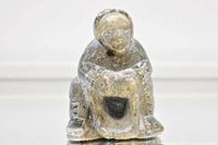 Front view of soapstone carving showing seated Inuit hunter figure with defined facial features and traditional clothing.