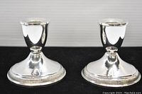 Two polished sterling silver candlesticks with round bases, showing front view.