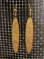 Close-up of brass Art Nouveau earrings showing detailed engraving, wire wrapped findings, and gold plated ear hooks.