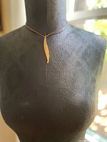Full view of the brass hammered pendant hanging on the silver plated chain displayed on a black mannequin bust showing overall length and style.