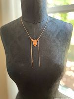 Full front view of the faery pendant necklace on a bust showing the pendant's shape and chain tassels