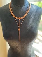 Full view of copper multi-chain necklace on display bust, showing the layering of the snake chain and the pendant chain with tassels.