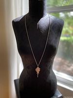 Full view of silver plated fish necklace displayed on black mannequin torso showing length and drape of chain with pendant hanging at chest.