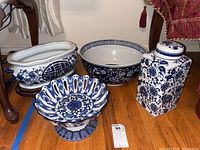 All four blue and white ceramic items placed on wooden floor, showing size, color, and shapes